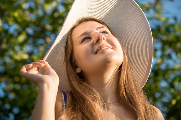 Beyaz şapkalı güneşe bakarak gülümseyen esmer kadın portresi — Stok fotoğraf