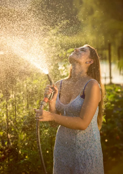 Jeune femme arrosage jardin avec tuyau d'arrosage — Photo