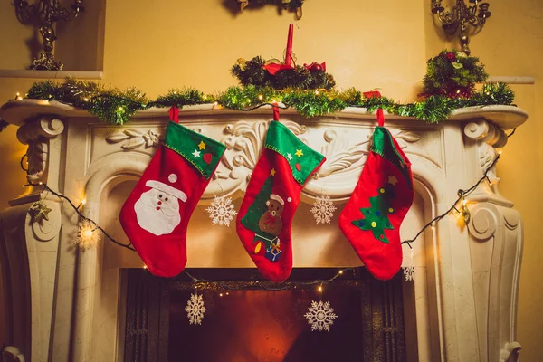 Toned photo of three red Christmas socks hanging on fireplace — Stock Photo, Image