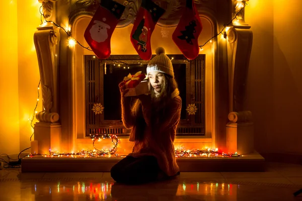 Κορίτσι που κάθεται στο σκοτεινό δωμάτιο διαβίωσης τα Χριστούγεννα και το ψάχνει στο εσωτερικό — Φωτογραφία Αρχείου