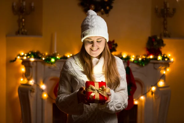 Happy woman in sweater holding glowing gift box at Christmas eve — Stock Photo, Image