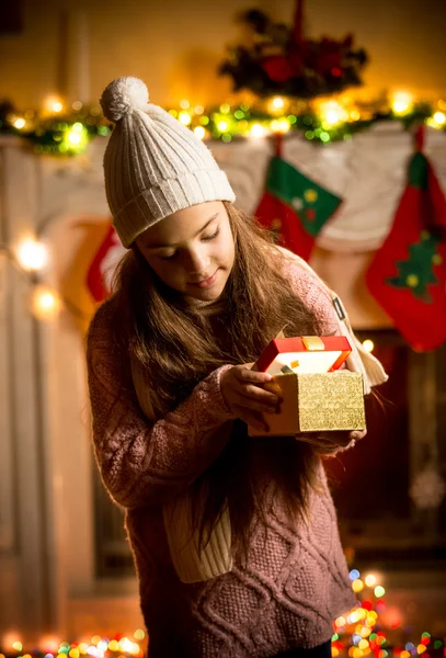 Menina vestindo suéter olhando na caixa de presente na véspera de Natal — Fotografia de Stock