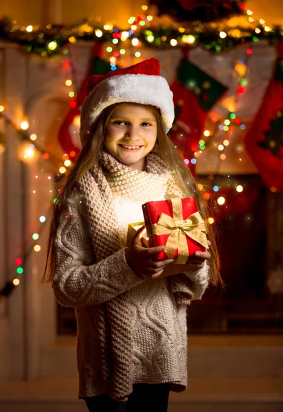 Niña en sombrero rojo sosteniendo caja de regalo brillante — Foto de Stock