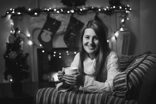 Retrato monocromático de la mujer sonriente bebiendo té en la chimenea a —  Fotos de Stock