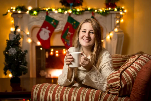 Woman sitting at fireplace with cup of tea at Christmas — Stock Photo, Image