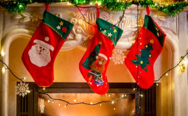 Bir şekilde dekore edilmiş şömine üzerinde asılı üç Noel çorap