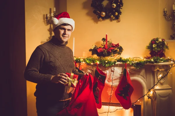 Fotoğraf gülümseyen adam hediye kutu kırmızı Santa çanta dışarı alarak tonda — Stok fotoğraf
