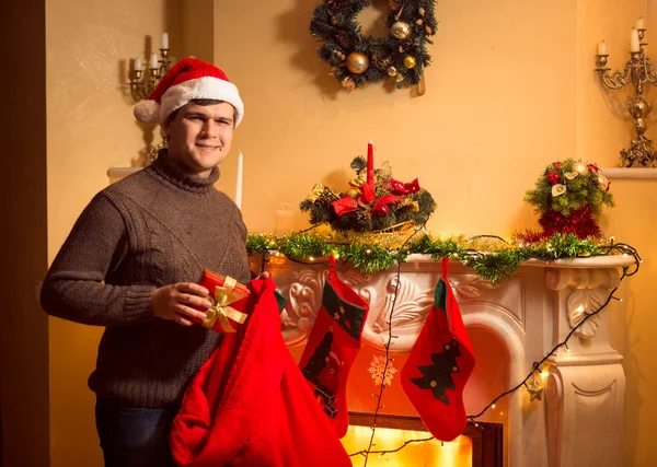 Gülümseyen adam hediyeleri Noel çorap f üzerinde asılı koyarak — Stok fotoğraf