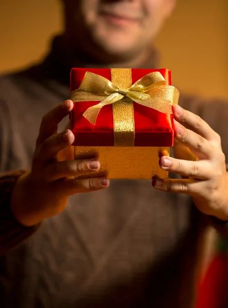 Hombre feliz sosteniendo caja de regalo roja con arco de oro —  Fotos de Stock