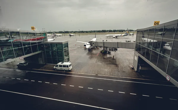 Luchthaven terminal met vliegtuigen op poorten instappen op regenachtige dag — Stockfoto
