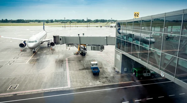 Avión de pasajeros estacionado junto a la puerta de embarque en la terminal del aeropuerto —  Fotos de Stock