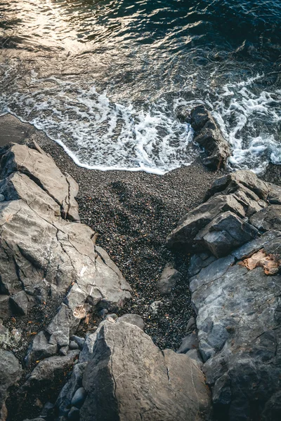Θαλάσσιο κύμα/τσουνάμι που καλύπτουν βράχους στο ηλιοβασίλεμα — Φωτογραφία Αρχείου