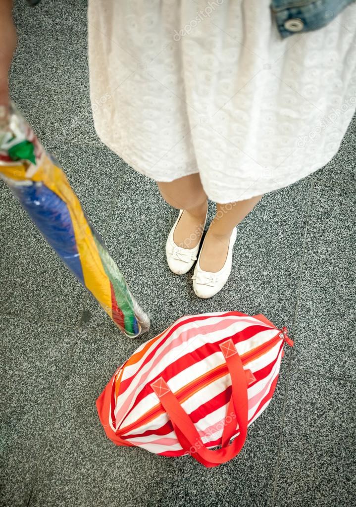 photo of female feet, sun umbrella and beach bag