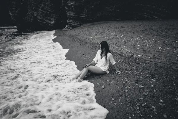 Foto monocromática de mujer joven en camisa blanca acostada en la playa de mar — Foto de Stock