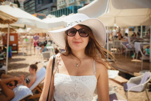 Beautiful woman wearing hat and sunglasses posing on beach — Stock Photo, Image