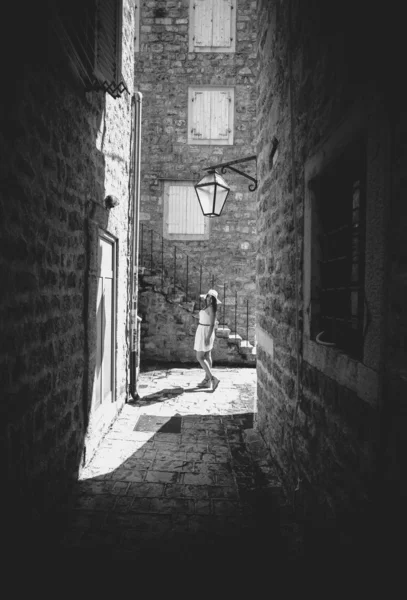 Monochrome photo of young woman walking at old narrow street — Stock Photo, Image