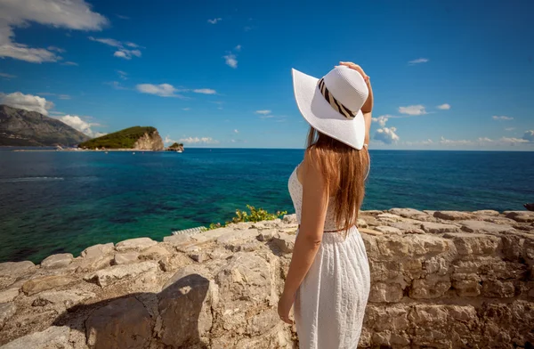 Woman standing on top sea shore and looking at island at sea — Stock Photo, Image