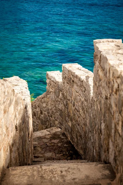 Antigua pared de piedra con escaleras que conducen al mar azul —  Fotos de Stock