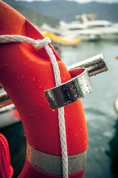 Photo of red lifebuoy with rope against sea port — Stock Photo, Image