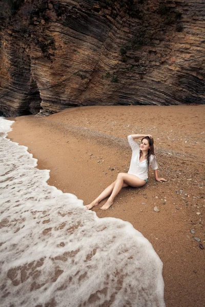 Brunette woman relaxing on deserted beach between cliffs — Stock Image Brunette woman relaxing on deserted beach between cliffs Stock Image