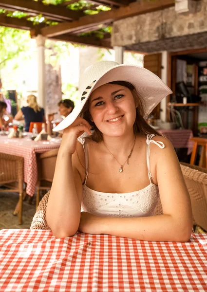 Lachende vrouw dragen witte hoed zitten in restaurant op open te — Stockfoto