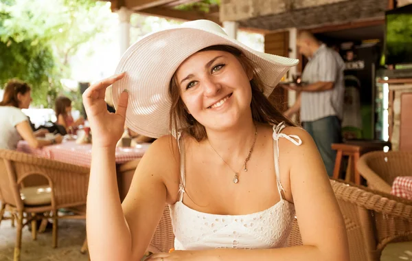 Wanita cantik tersenyum dengan topi putih duduk di kafe di hari yang cerah — Stok Foto