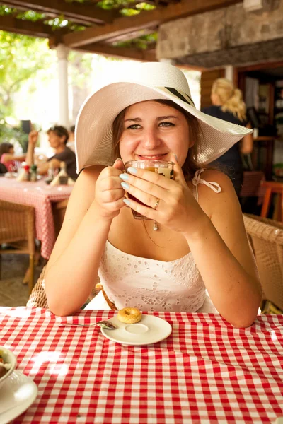 Ung kvinna dricka te på café på solig morgon — Stockfoto