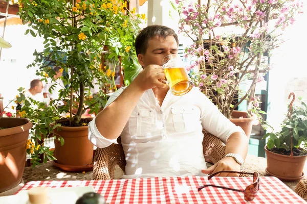 Young man drinking beer at hot day on restaurant summer terrace — Stock Photo, Image