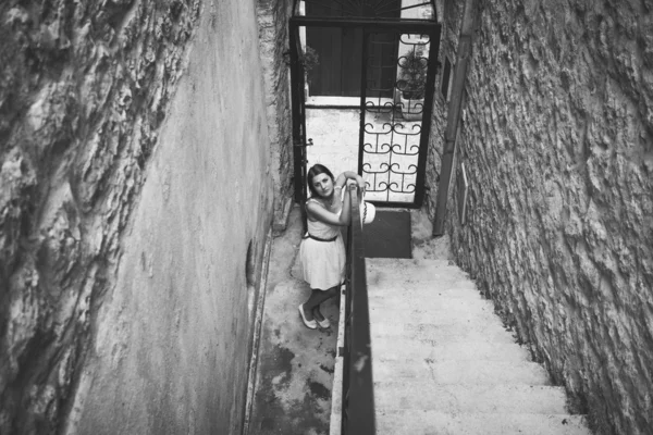 Monochrome photo of young woman standing at entrance old buildin — Stock Photo, Image