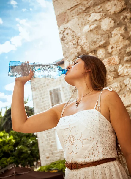 Wanita berambut cokelat muda minum air dari botol pada hari yang cerah — Stok Foto