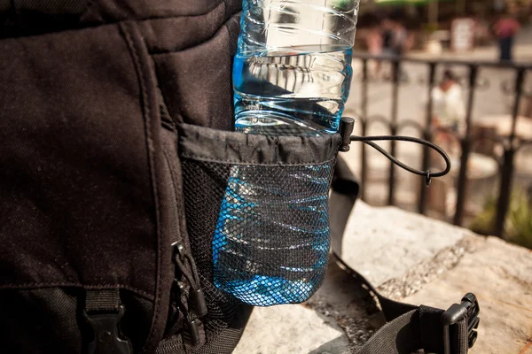 Plastic fles water in zwarte rugzak — Stockfoto