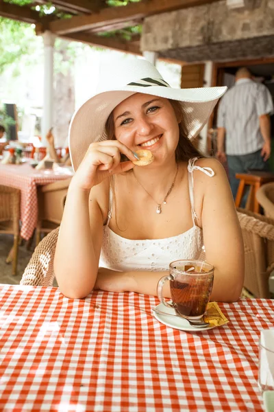 Portret van lachende vrouw cookie eten en het drinken van thee in café — Stockfoto