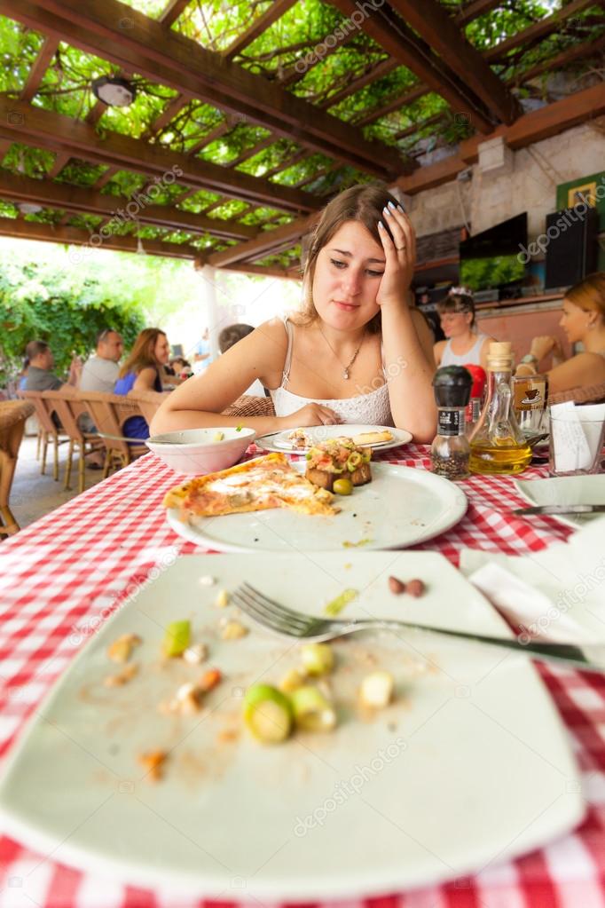 young woman looking at empty plates at restaurant