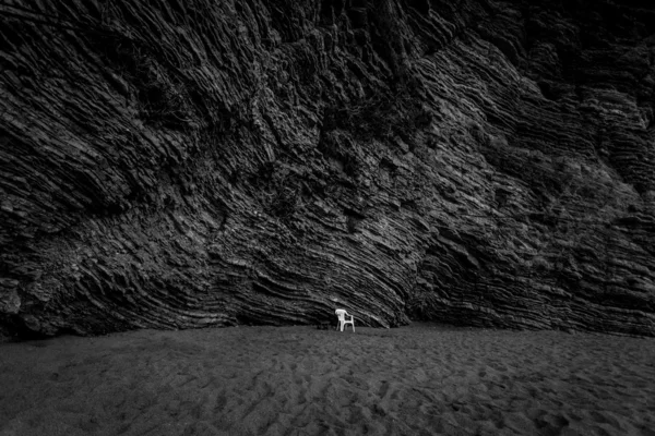 Монохромний знімок безлюдного пляжу з високою скелею — стокове фото