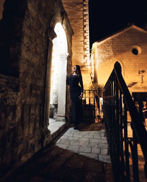 Night shot of sexy woman posing next to old stone arch — Stock Photo, Image