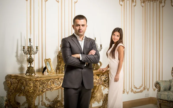 Handsome man in suit posing at classic interior with woman — Stock Photo, Image