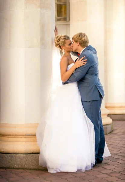 Newly married couple kissing against old column — Stock Photo, Image