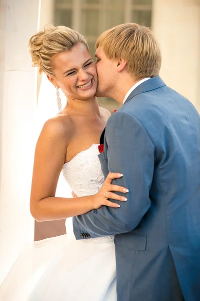 Portrait of young groom kissing bride on street at sunny day — Stock Photo, Image