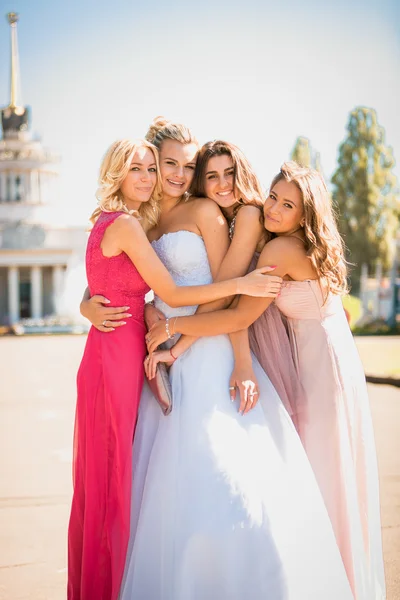 Beautiful bride hugging with bridesmaids at sunny day — Stock Photo, Image