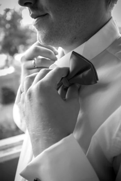 Black and white photo of elegant man adjusting bow tie — Stock Photo, Image