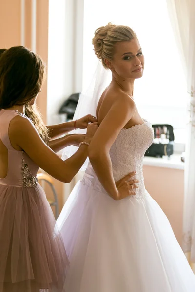 Mother assisting bride in putting wedding dress on — Stock Photo, Image