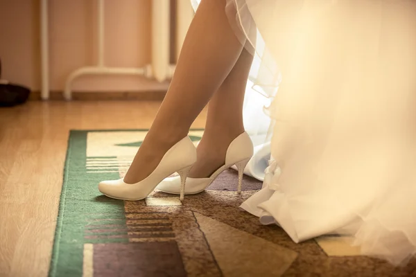 Closeup photo of bride putting on white shoes — Stock Photo, Image