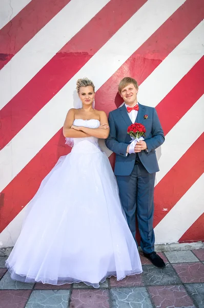 Feliz hipster casado pareja posando contra rojo rayas pared —  Fotos de Stock
