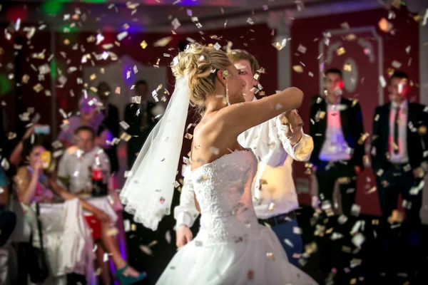 Blonde bride dancing at restaurant in flying confetti Stock Photo