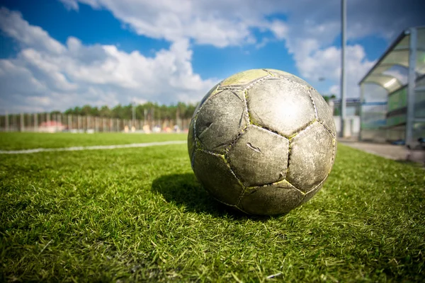 Old soccer ball on grass field at sunny day — Stock Photo, Image