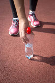 sportovní ženy brát láhev vody z běžecké dráhy