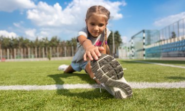 Genç kız futbol sahası bacaklarına güneşli gün germe