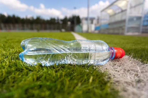 Plastik şişe su çim futbol sahası üzerinde yalan — Stok fotoğraf