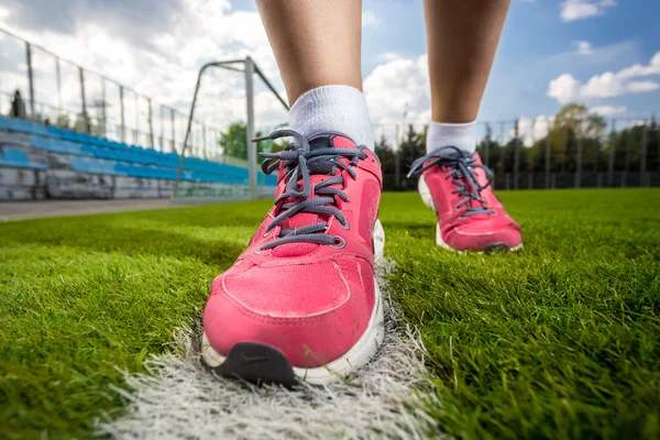 Foto de sapatilhas femininas rosa no campo de futebol grama — Fotografia de Stock