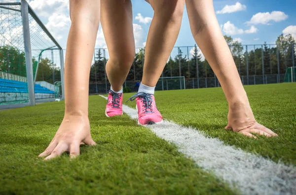 Schlanke, sportliche Frau bereitet sich auf den Lauf auf der Rasenbahn vor — Stockfoto